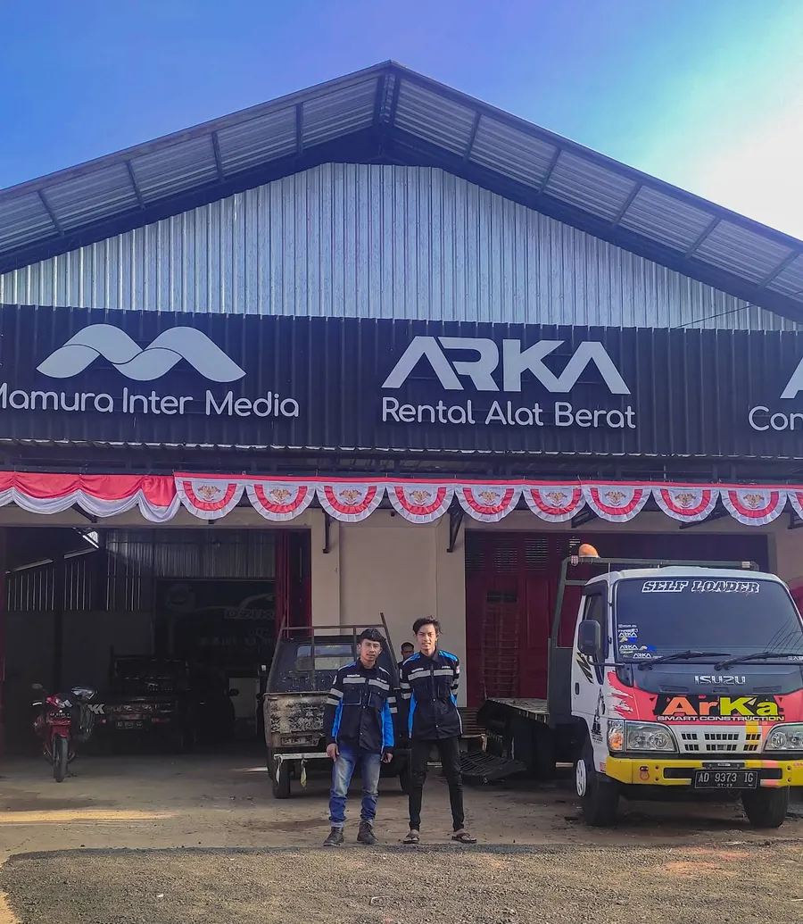 Dua pria berdiri di depan kantor ARKA Rental Alat Berat, dengan sebuah truk di sebelahnya