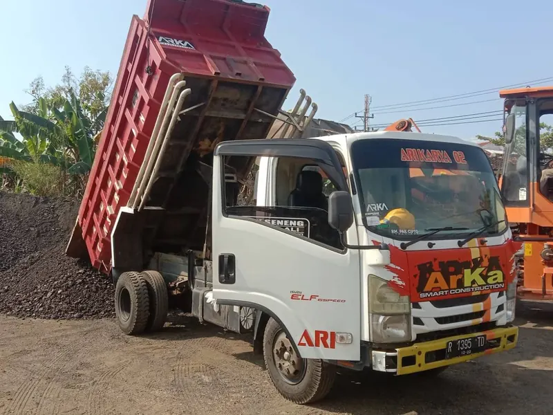 Dump truk ARKA menurunkan muatan di dekat tumpukan material