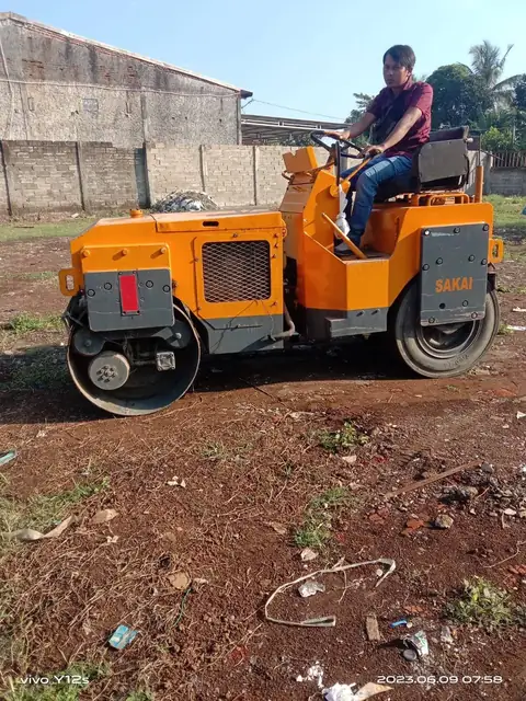 Seorang pria mengendarai roller kecil oranye di tanah merah