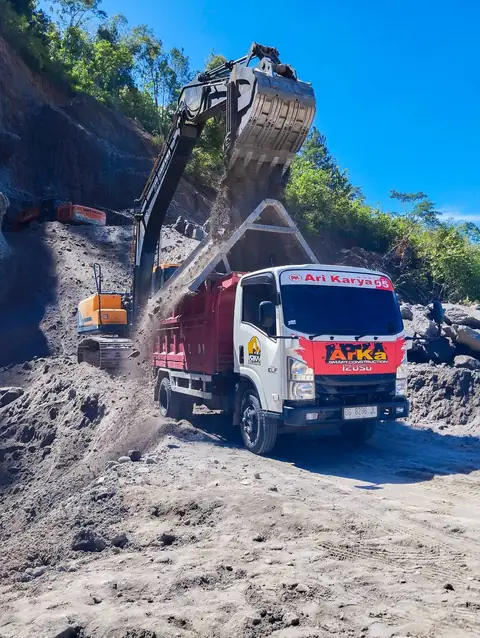 Ekskavator mengisi bak dump truk ARKA dengan tanah berpasir di lereng