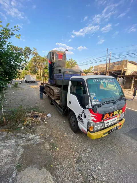 Truk bergambar ARKA membawa alat di baknya di tepi jalan
